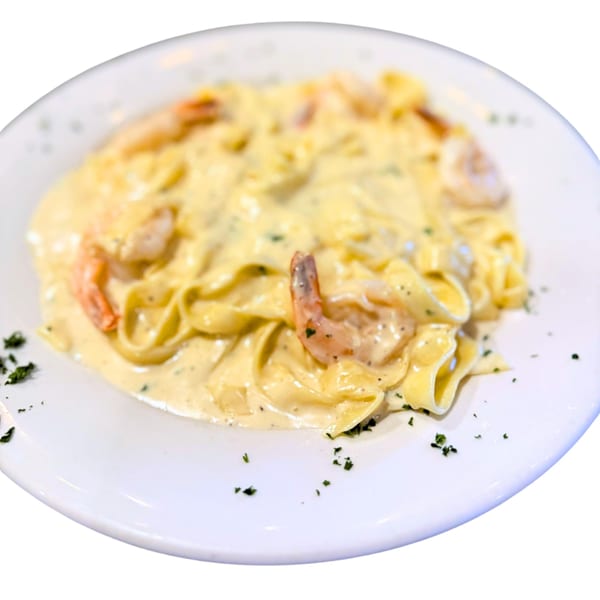 Creamy fettuccine Alfredo with shrimp and parsley on a white plate from Amore Pasta & Pizza.