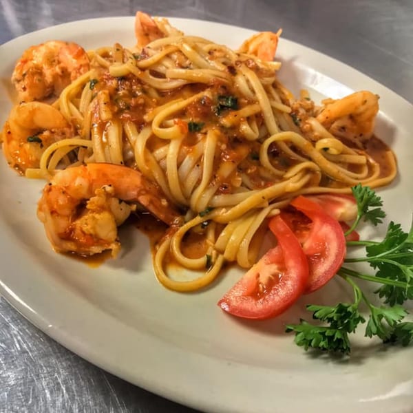 Amore Pasta & Pizza's shrimp linguine with red sauce, garnished with tomato slices and parsley.