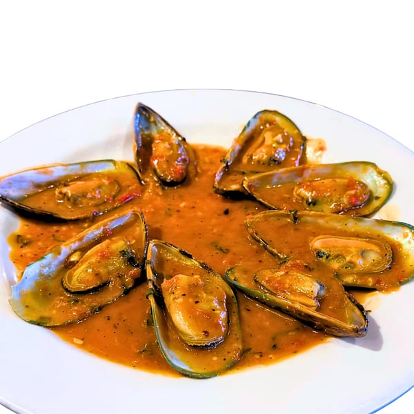 A plate of mussels in a rich, orange-red sauce, garnished with herbs.