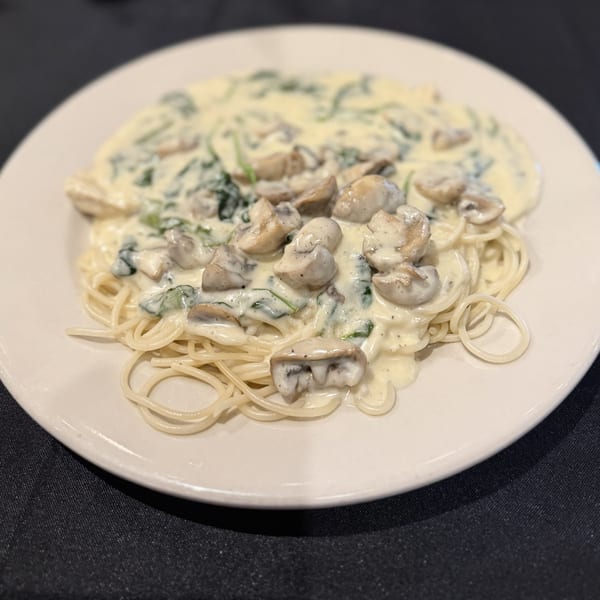 Amore Pasta & Pizza's spaghetti with creamy mushroom and spinach sauce on a white plate.