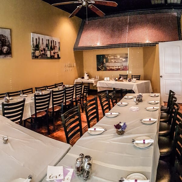 Amore Pasta & Pizza dining room with tables set for a banquet, featuring wine bottle art.