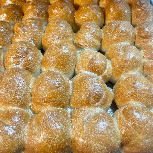 Close-up of golden-brown Italian garlic knots, glistening with butter and sprinkled with salt.